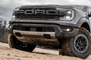 2025 Ford Ranger Raptor driving off-road with dust trail behind