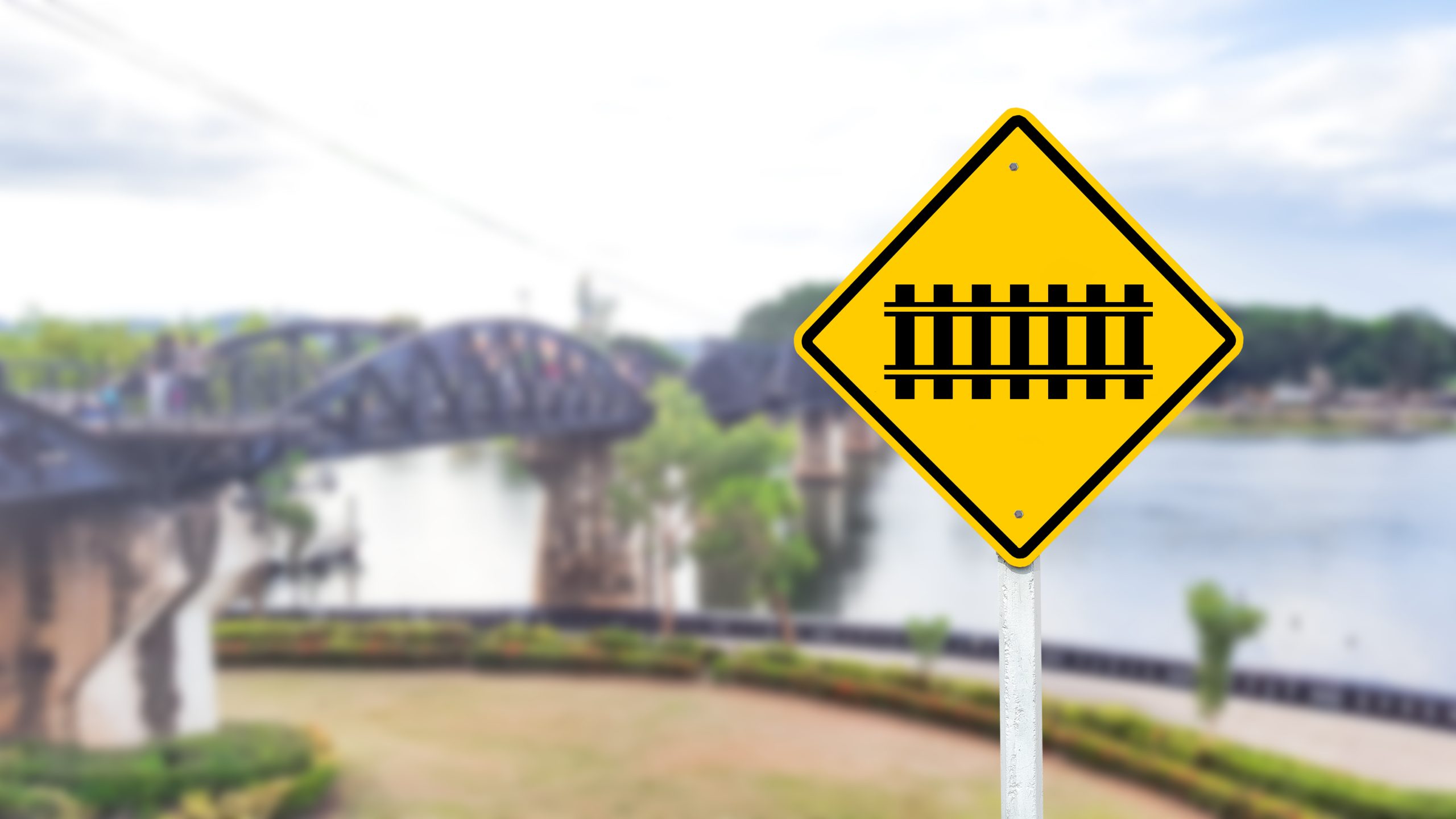 A black railway crossing symbol is prominently displayed on a bright yellow sign. This warning sign alerts drivers and pedestrians to the presence of a railroad crossing ahead. promoting safety and caution in the area. A black railway crossing symbol is prominently displayed on a bright yellow sign. This warning sign alerts drivers and pedestrians to the presence of a railroad crossing ahead. promoting safety and caution in the area.